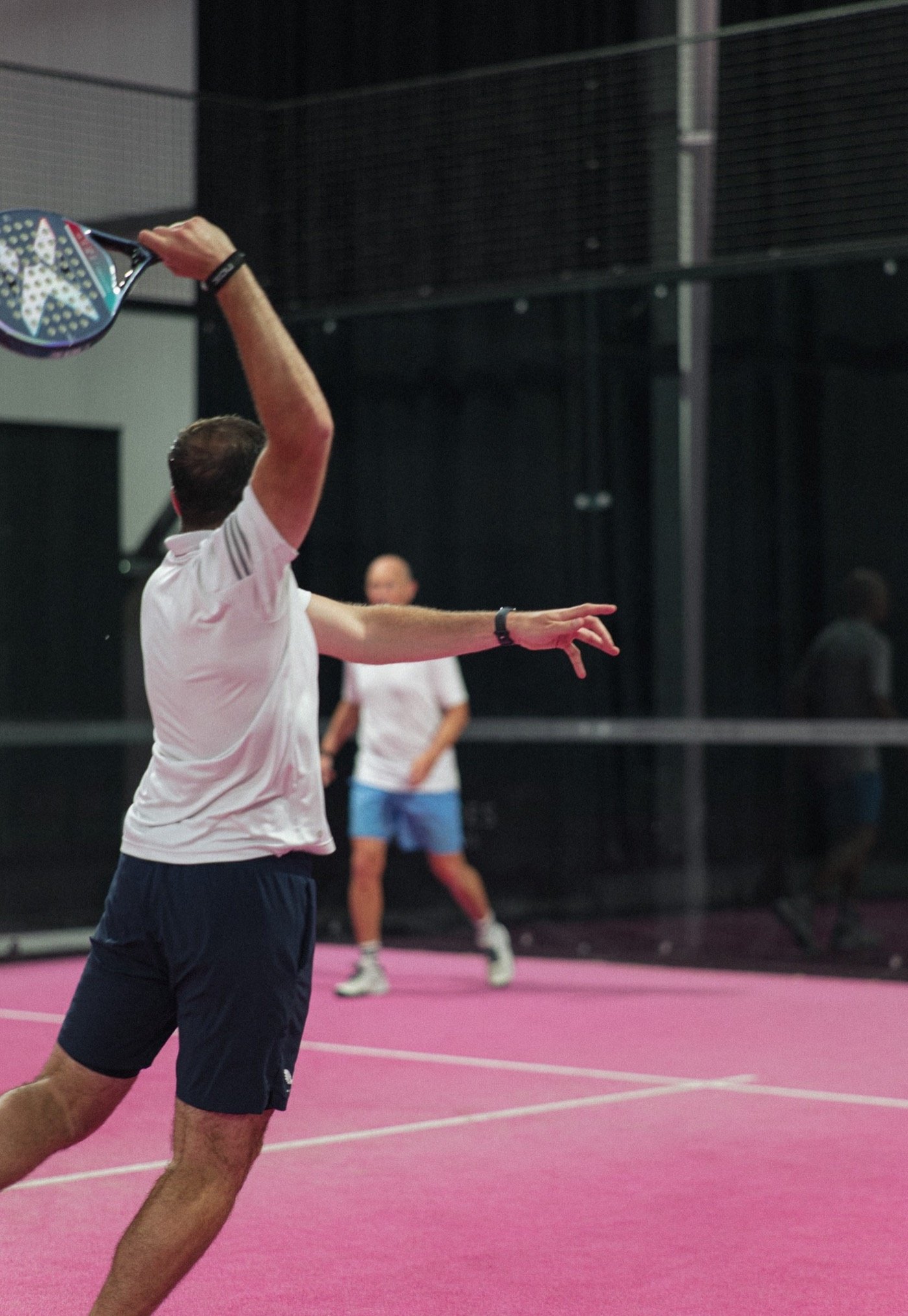 Padel player mid-shot on a pink court