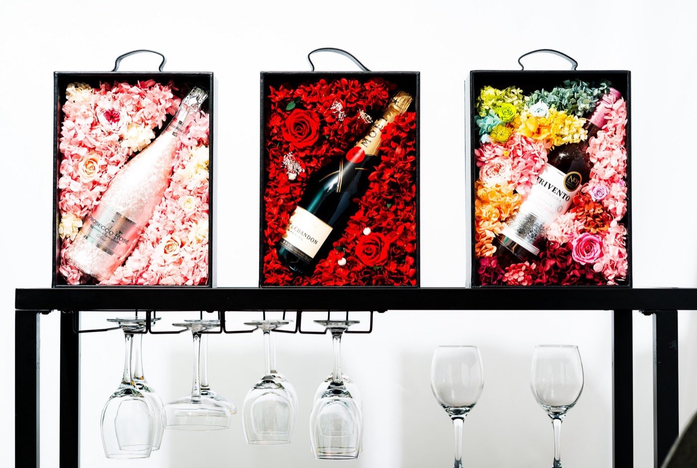Wine bottles in red, flower-filled gift boxes