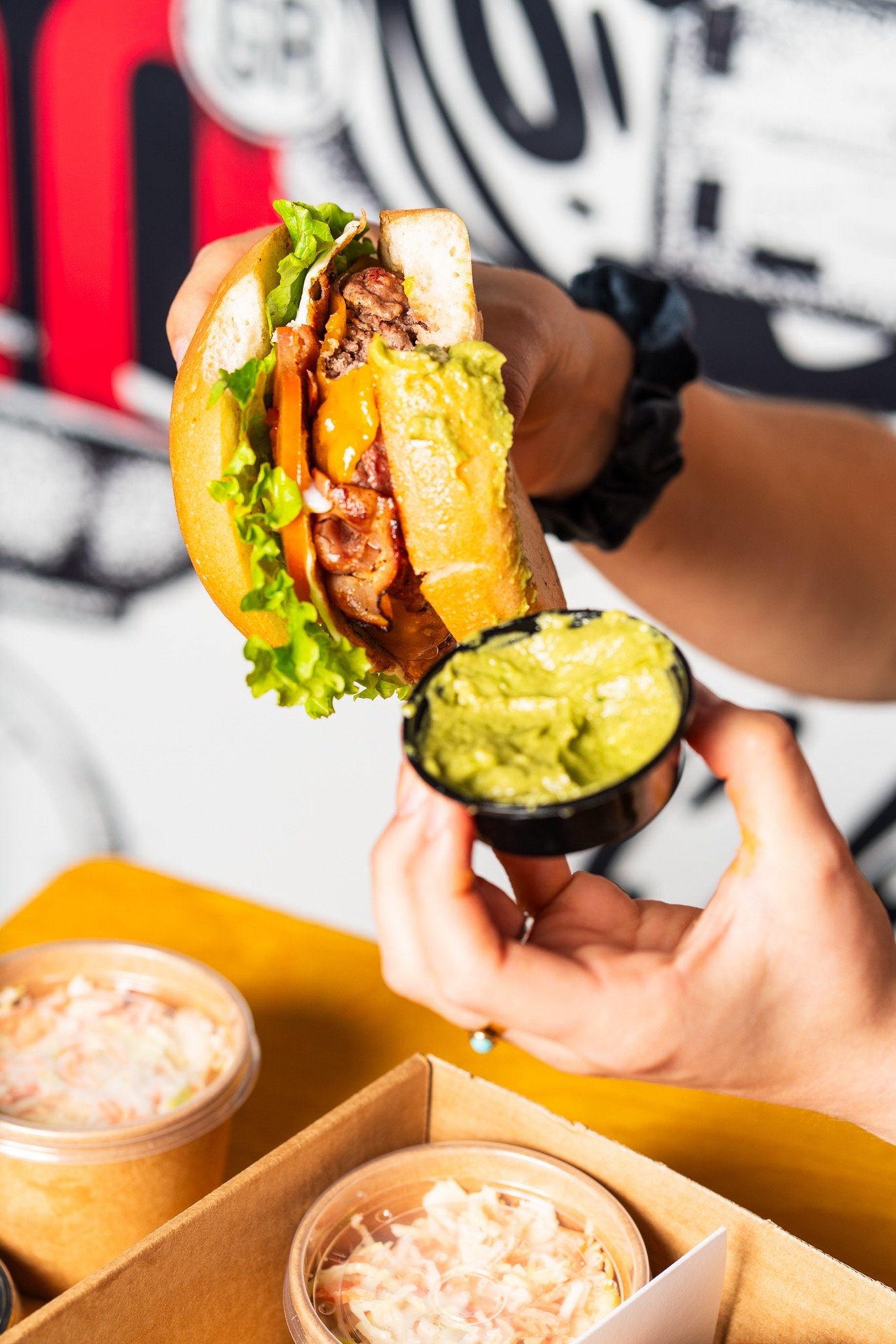 Burger and guacamole held over a takeaway box