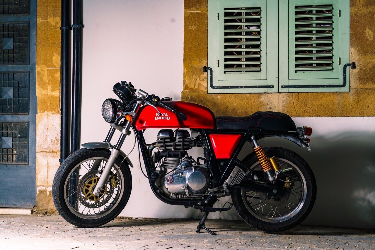 Royal Enfield motorcycle by a wall with green shutters