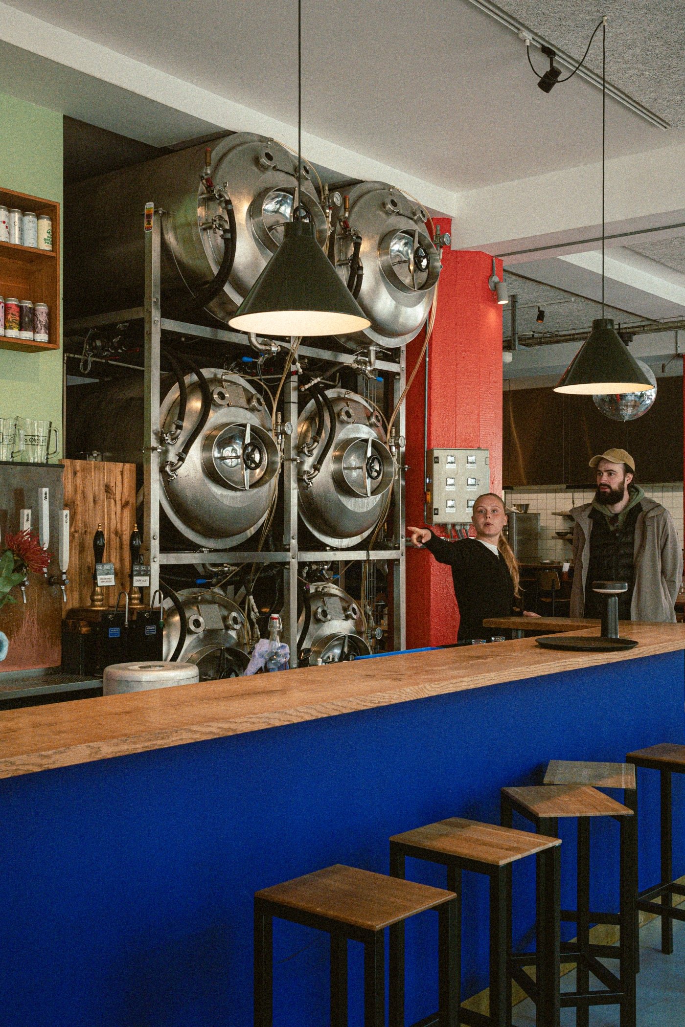 Brewpub bar with a blue counter and steel tanks in Copenhagen