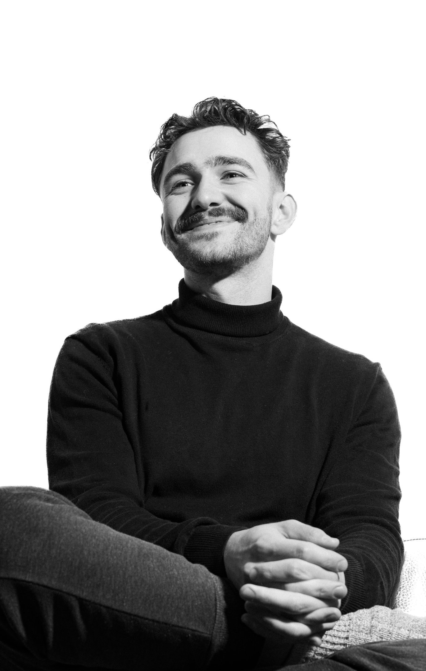 Black-and-white portrait of a smiling man in a dark jumper