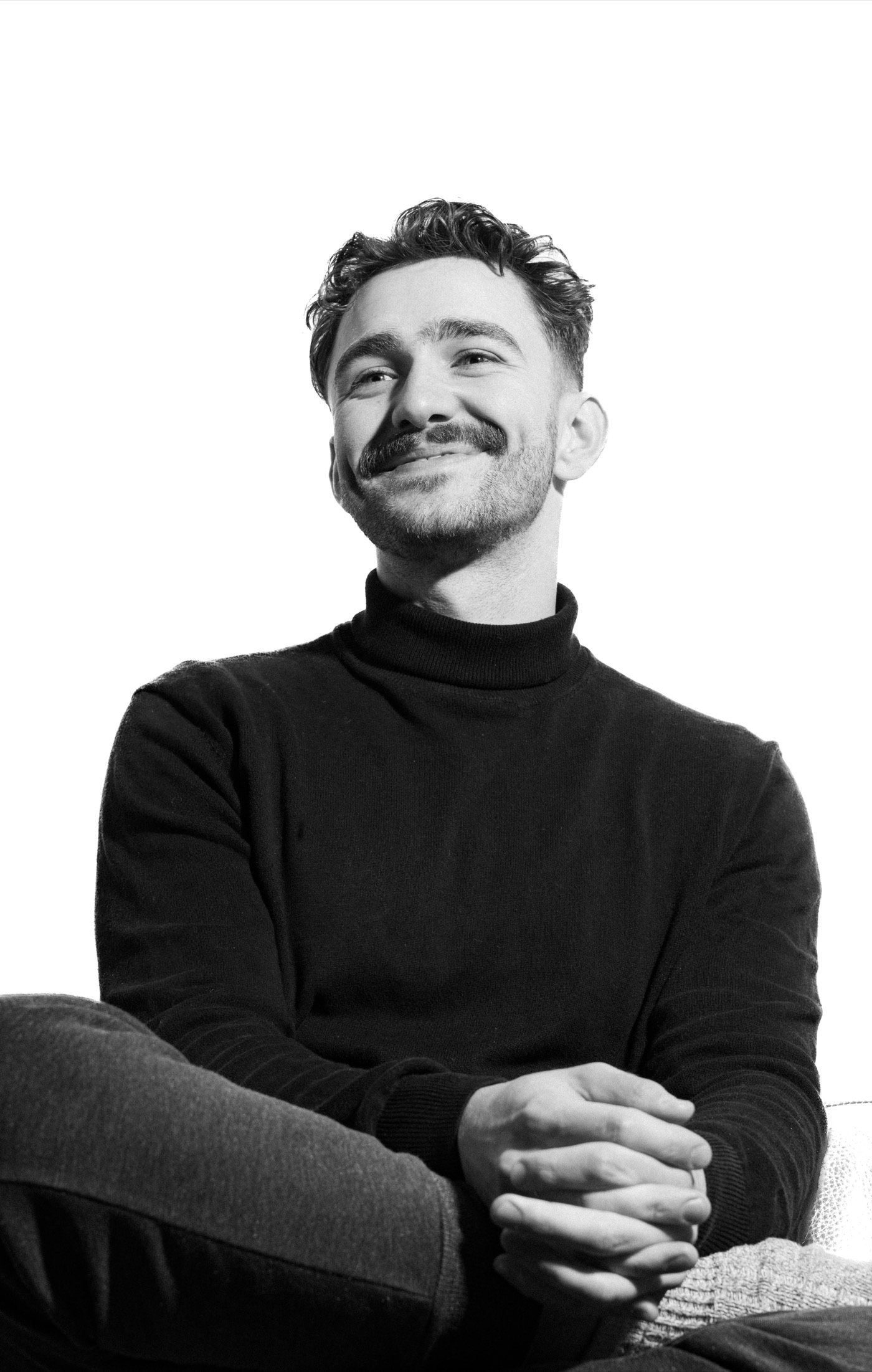 Black-and-white portrait of a smiling man in a dark jumper