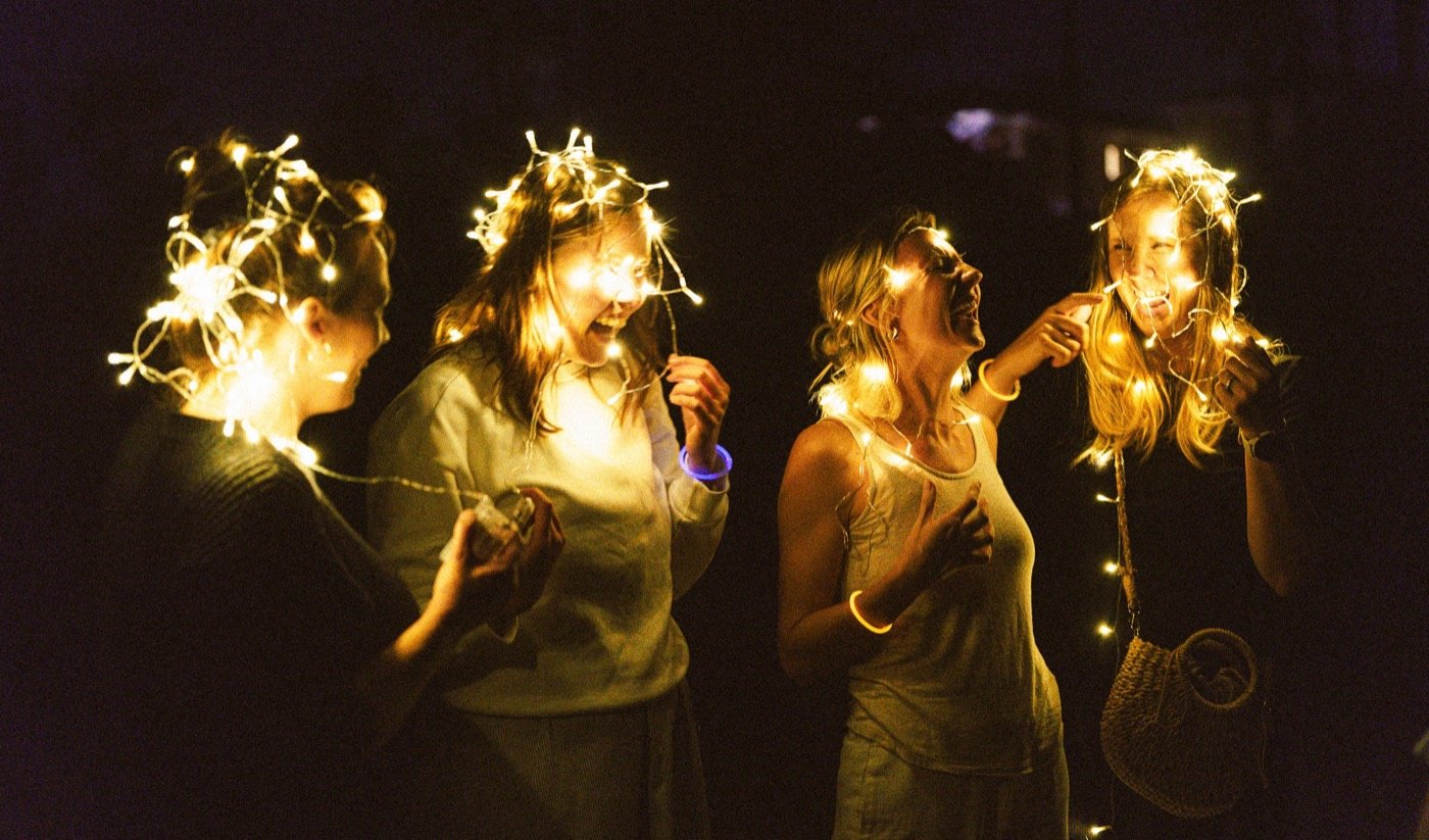 Friends wrapped in fairy lights at night