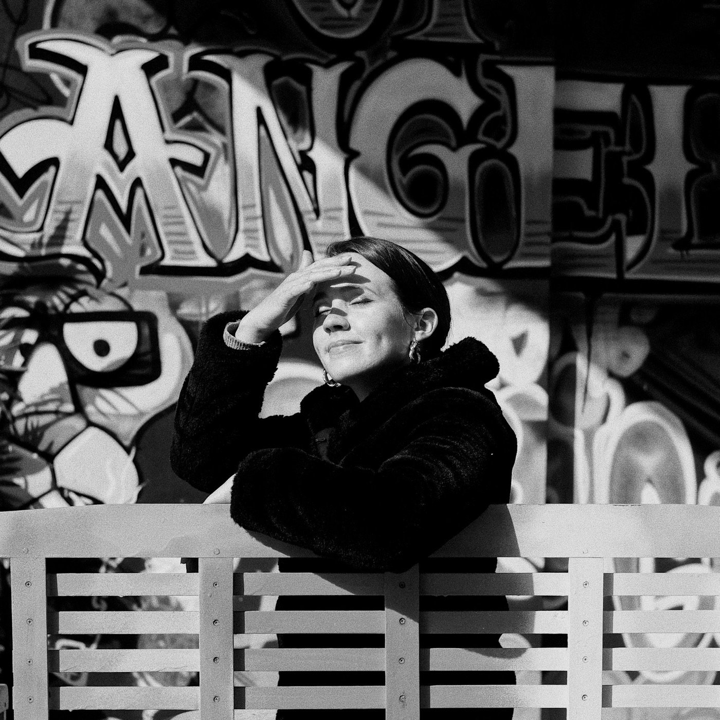 Black-and-white street portrait beneath a large sign