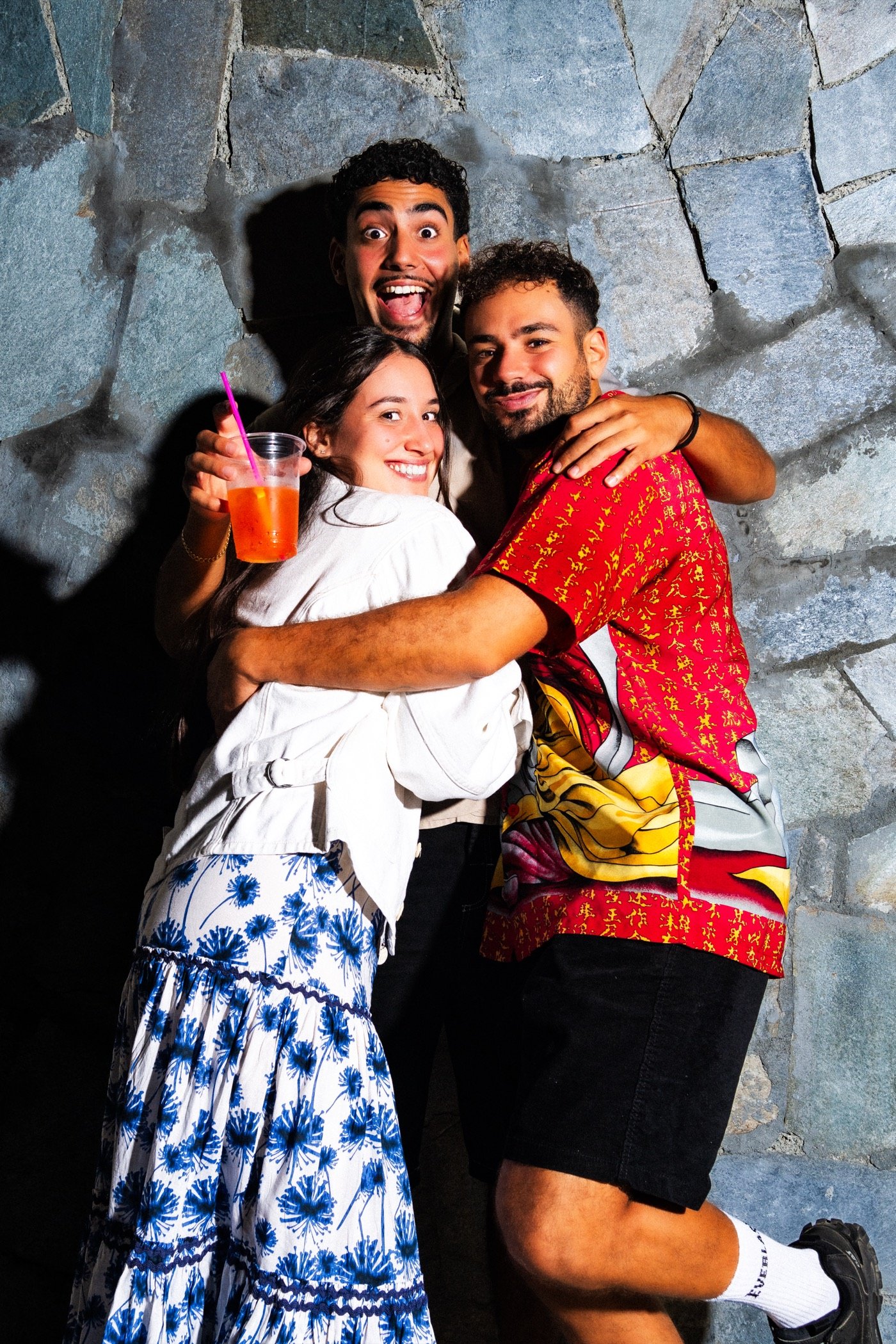 Friends hugging against a stone wall