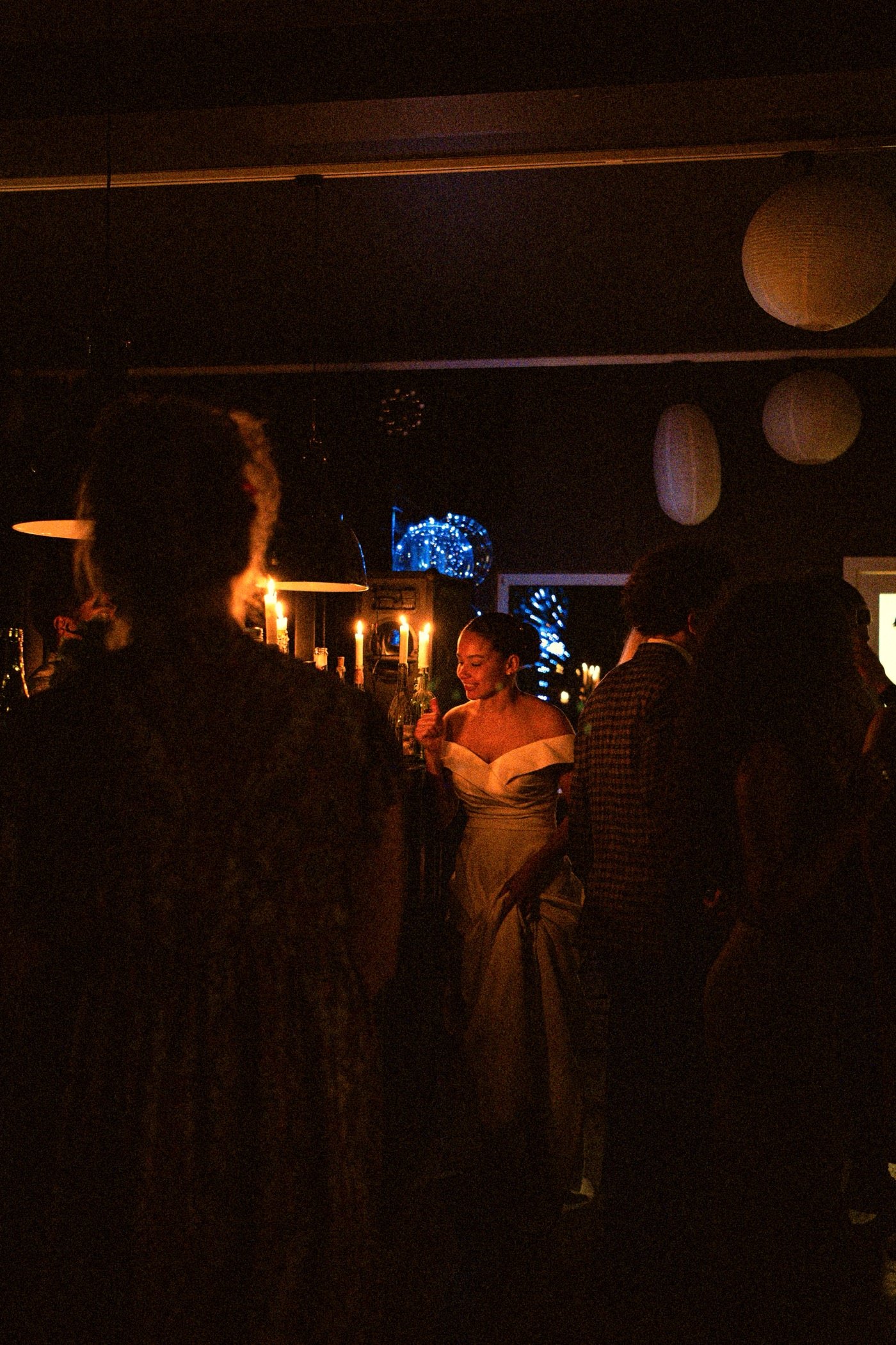 Woman in a white dress across a candlelit room