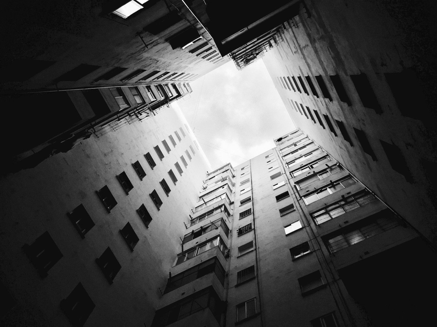Black-and-white view looking up between buildings