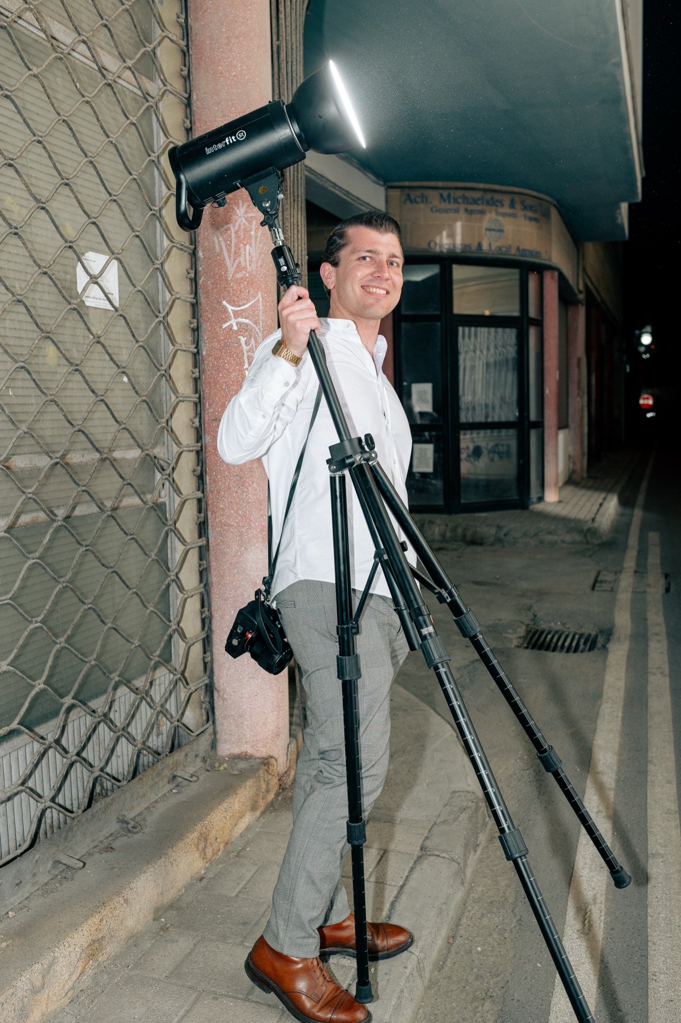 Joel May on a shoot in Cyprus, holding a studio strobe on a stand