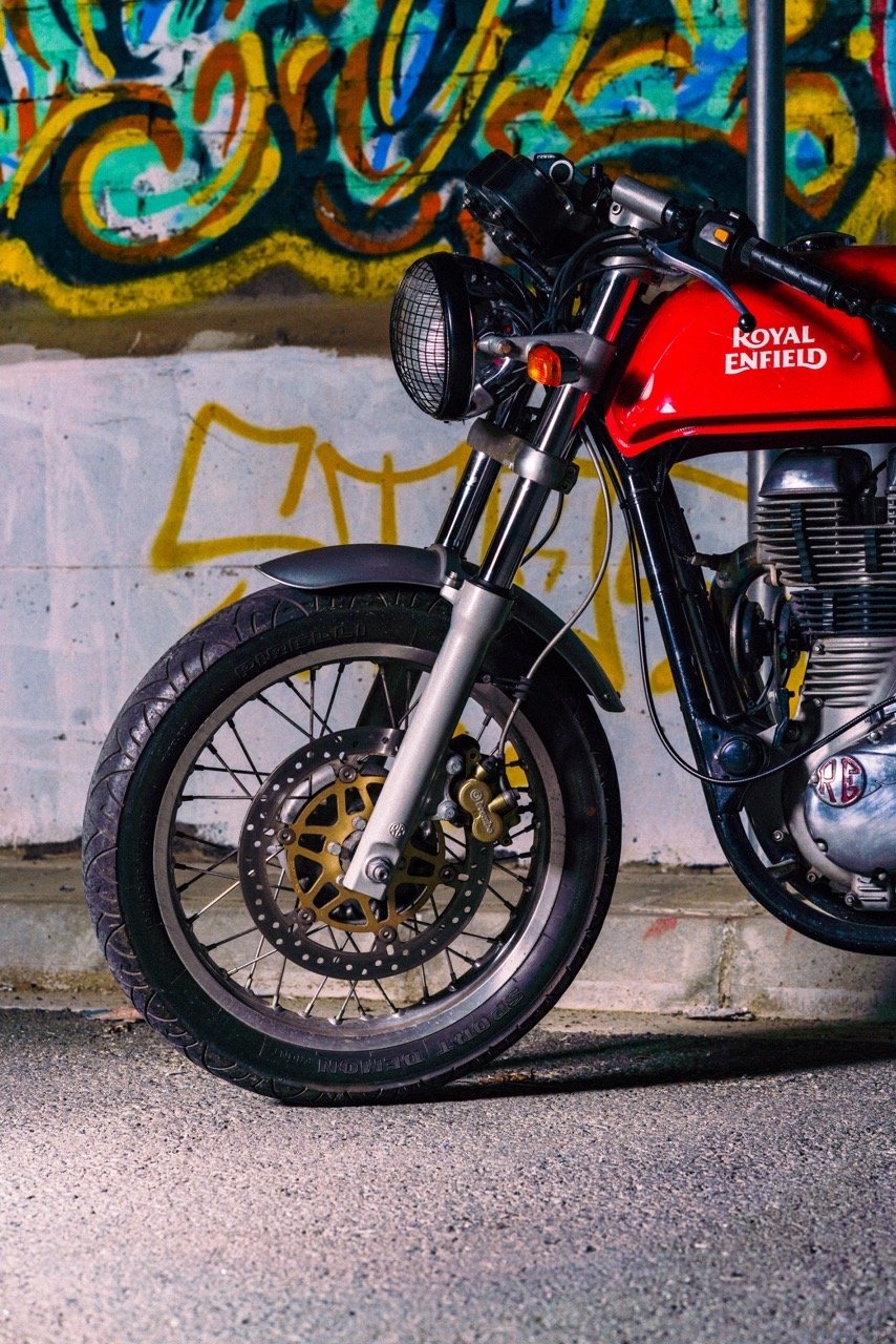 Red Royal Enfield motorcycle parked against a graffiti wall